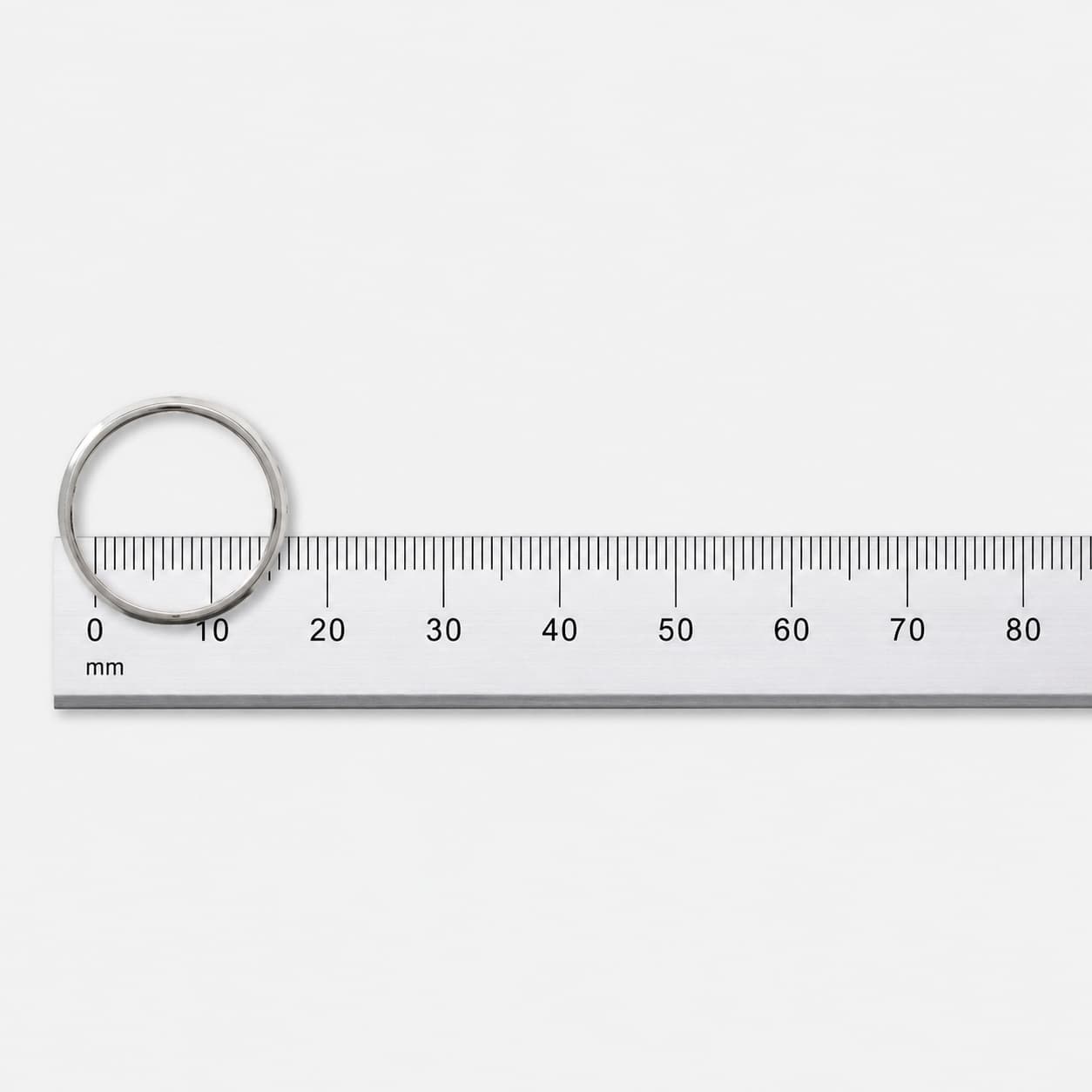 Primer plano de un anillo apoyado sobre una regla, midiendo su diámetro interior en milímetros.